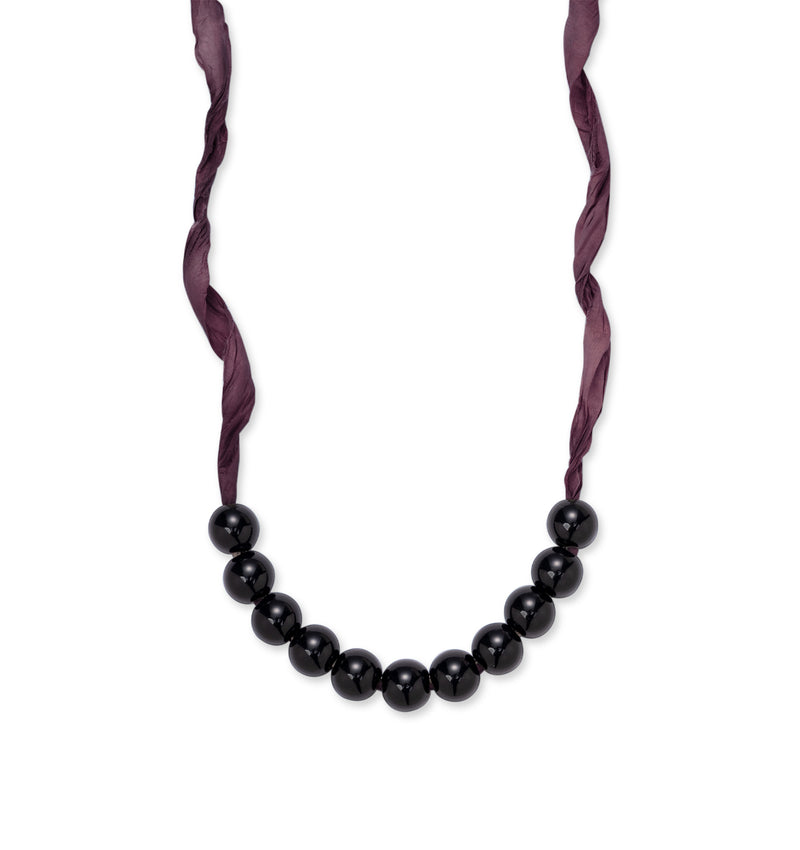 Des perles noires en résine sur un ruban bordeaux