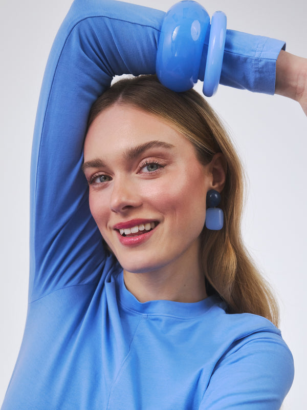 Niebieskie geometryczne kolczyki w połączeniu z pierścionkami z żywicy oraz emaliowanymi