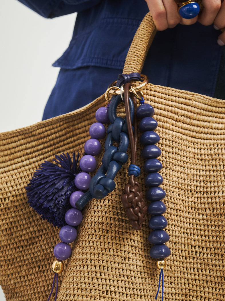  Skórzany niebieski pleciony brelok - zestaw skórzanych i żywicznych breloków przy jasnej letniej torebce 