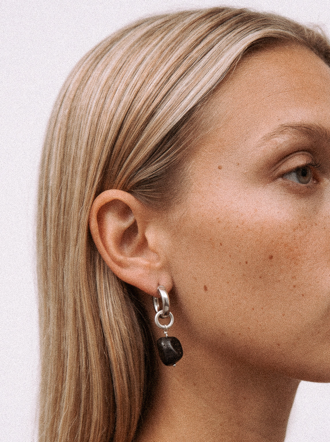 Srebrny kolczyk z czarną zawieszką z żywicy na modelce. 